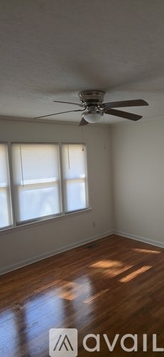 A room with a ceiling fan and wooden flooring.
