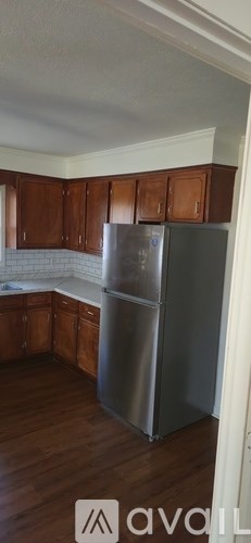 A kitchen with wooden cabinets and a stainless steel refrigerator.