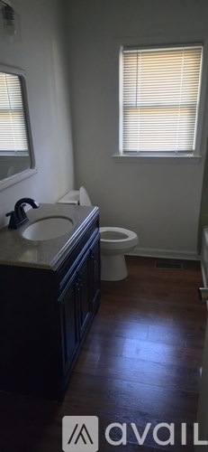 A bathroom with a toilet, sink, and window.