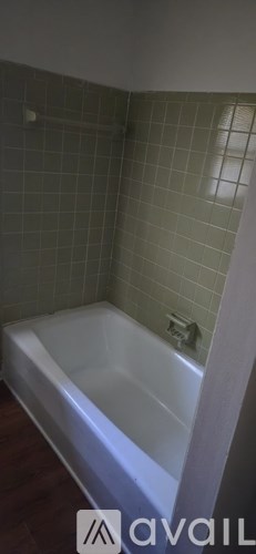 A white bathtub in a bathroom with green tiled walls.