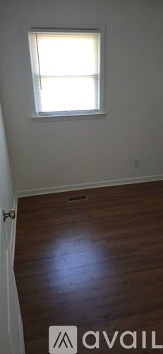 A room with a window and wooden flooring.