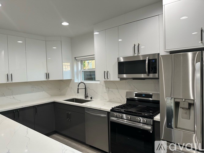 A modern kitchen with black cabinets and stainless steel appliances.