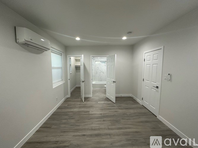 A spacious room with wood flooring and white walls.