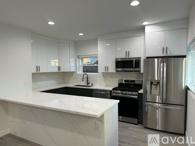 A modern kitchen with stainless steel appliances and white marble countertops.