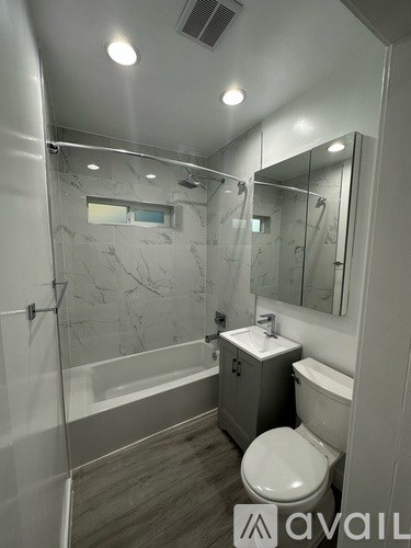 A bathroom with a marble patterned shower and a toilet.