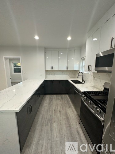A modern kitchen with a white countertop and black appliances.