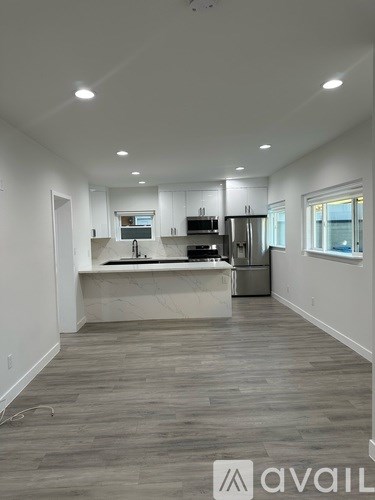 A modern kitchen with white cabinets and a marble island.