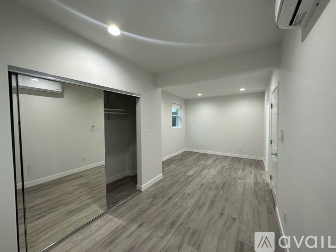 A spacious room with wood flooring and a large mirror on the wall.