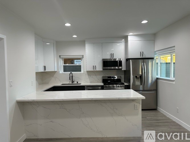 A modern kitchen with a marble countertop and stainless steel appliances.