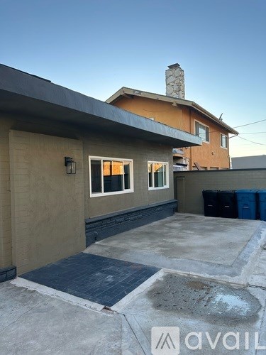 A house with a brown roof and a blue trash can.