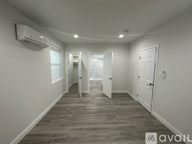 A spacious room with wood flooring and white walls.