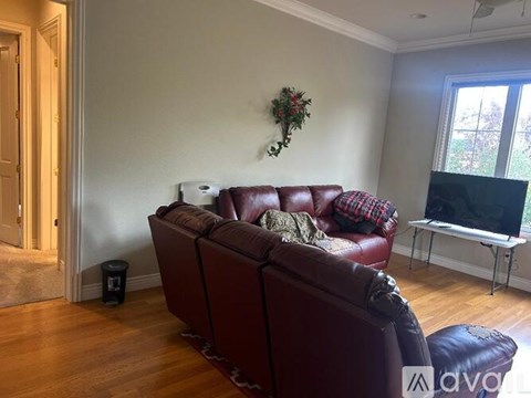 A living room with a red couch and a TV on a stand.