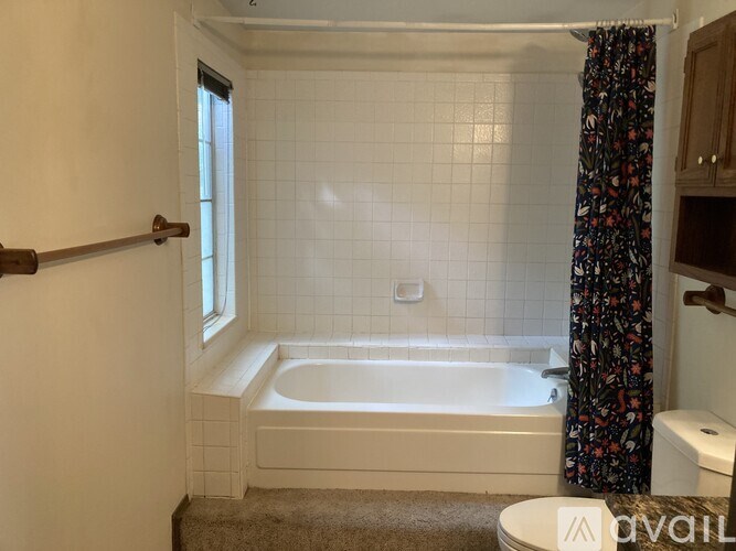 A white bathroom with a bathtub, toilet, and a window.