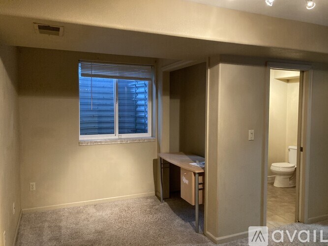 A room with a desk and a window with blinds.