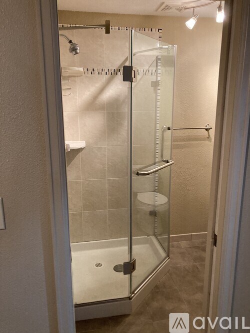 A glass shower stall with a glass door and a glass shelf.