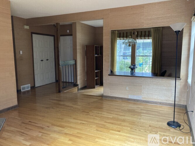 A room with wooden floors and a large window with curtains.