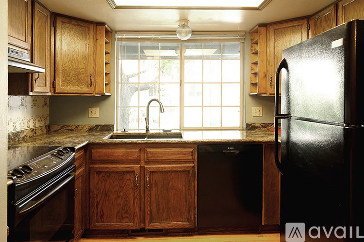 A kitchen with wooden cabinets and a black refrigerator.