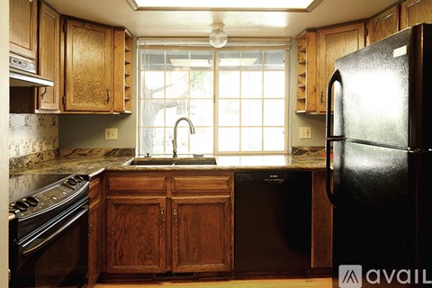 A kitchen with wooden cabinets and a black refrigerator.