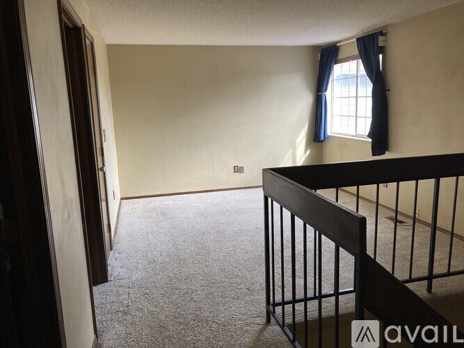 A carpeted room with a window and a railing.
