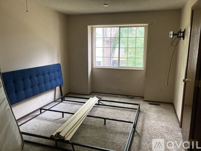 A room with a blue tufted headboard and a large window.
