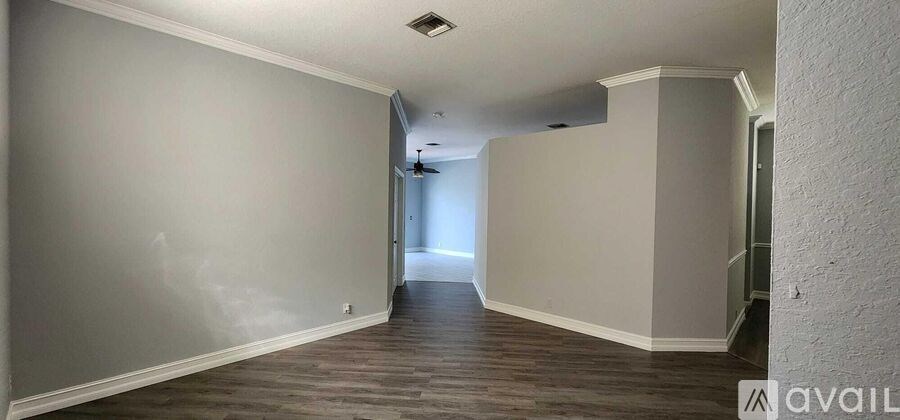 A long, empty hallway with wooden floors and white walls.