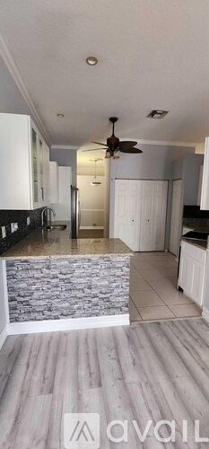 A kitchen with a ceiling fan and a stone counter.