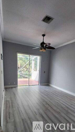 A room with a ceiling fan and sliding glass doors.