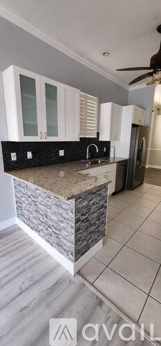A kitchen with white cabinets and a stone counter.