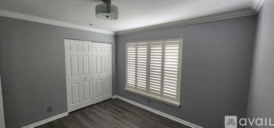 A room with a white door and a window with white shutters.