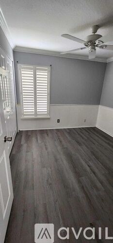 A room with a ceiling fan and wooden flooring.