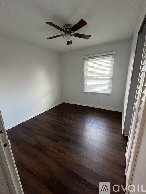 A room with a ceiling fan and wooden flooring.