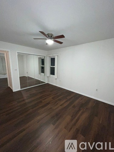 A room with a ceiling fan and wooden flooring.