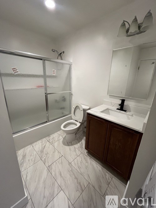 A bathroom with a toilet, sink, mirror, and washing machine.