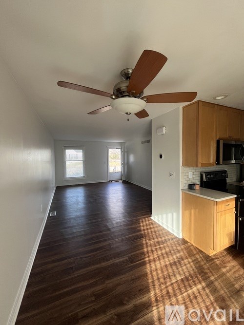 A room with a ceiling fan and two windows.