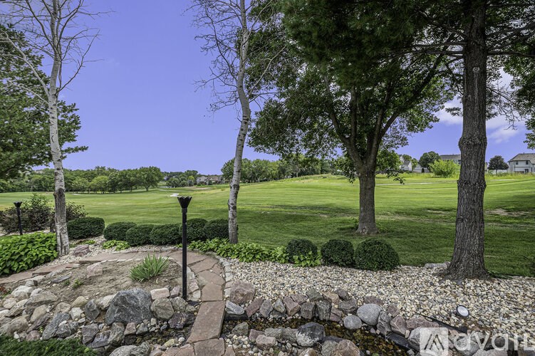 A stone pathway leads through a garden with a lamp post on the left.