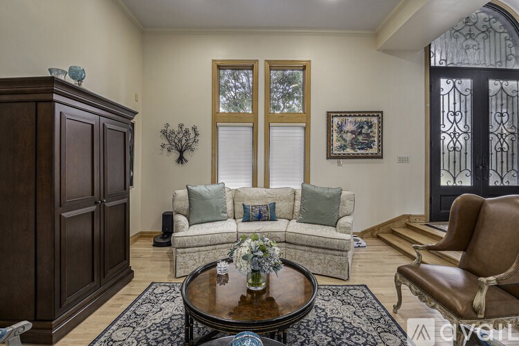 A living room with a brown leather chair and a coffee table with a vase of flowers on it.