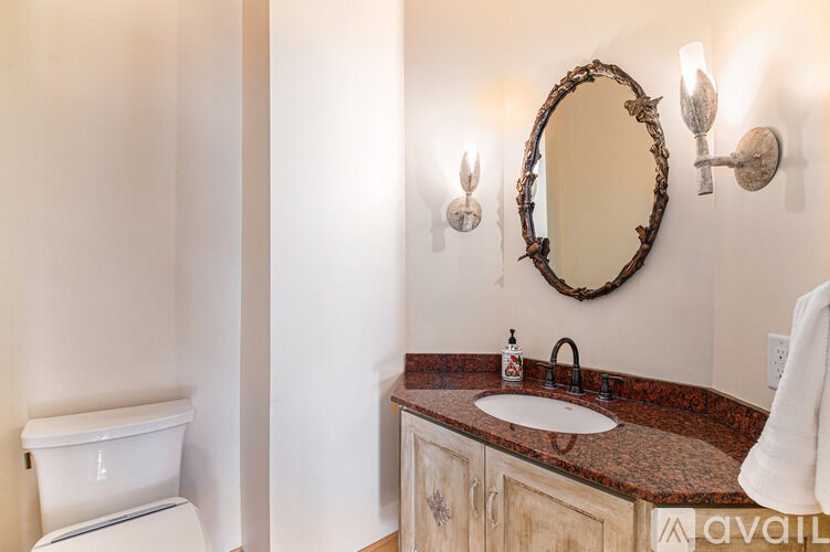 A bathroom with a toilet, sink, and mirror.