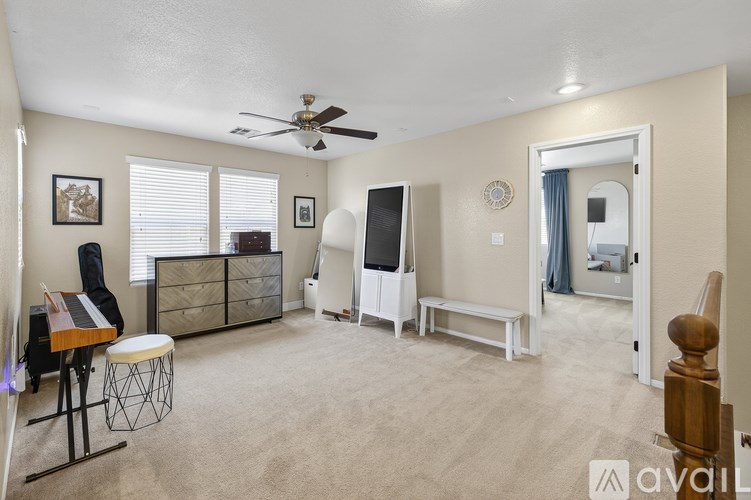 A living room with a white ceiling fan and beige walls.