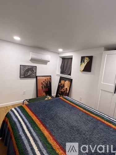 A bedroom with a bed covered in a multicolored blanket and pictures on the wall.