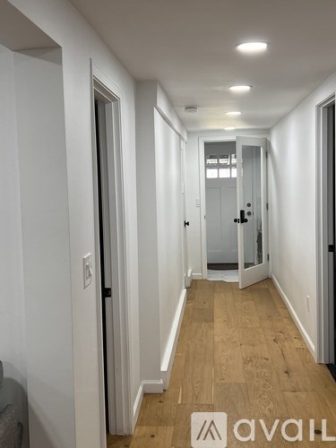 A hallway with wood flooring and white walls.
