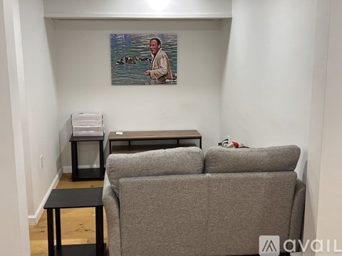 A living room with a grey couch, a small table, and a painting on the wall.