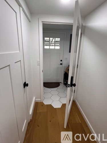 A hallway with a white door and a tiled floor.