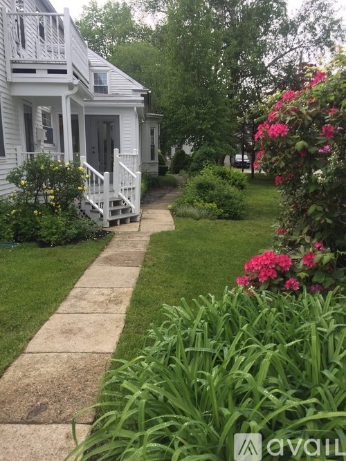A white house with a porch and a garden in front.