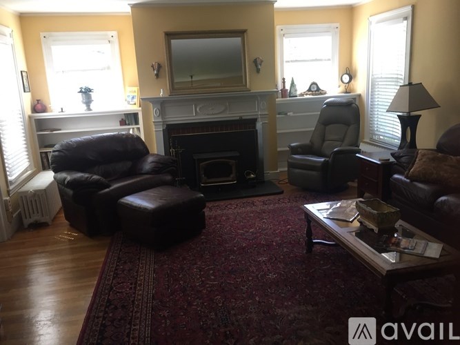 A living room with a fireplace, two chairs, and a rug.
