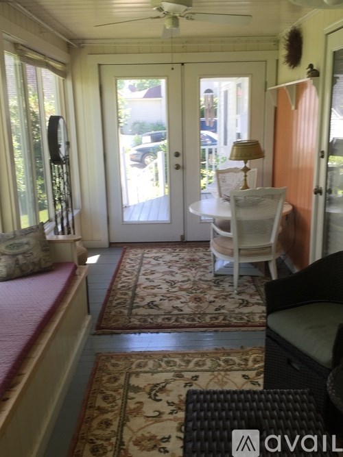 A living room with a rug on the floor and a fan on the ceiling.