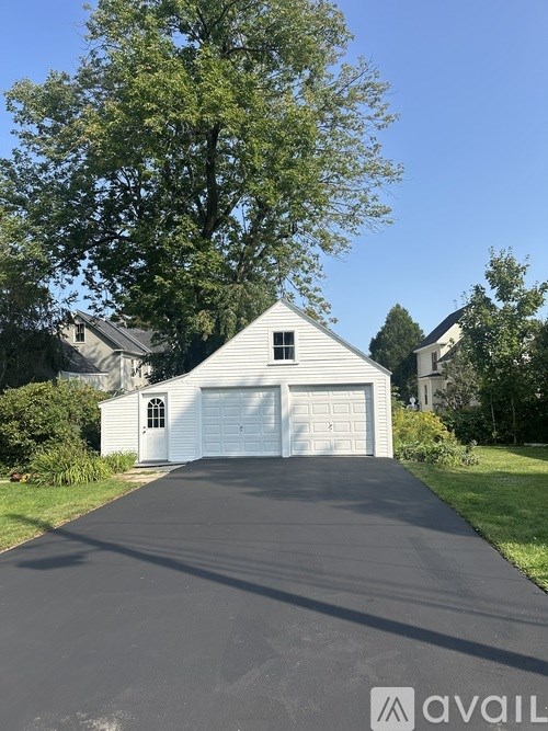 A residential house with a white garage door and a driveway.