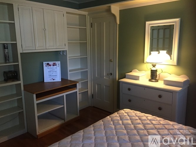 A room with a bed, a dresser, and a cabinet with a sign on it.