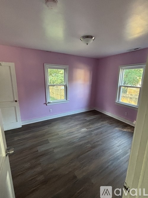 A room with purple walls and wood flooring.