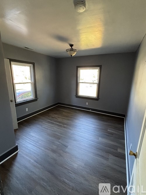 A room with grey walls and wooden flooring with a ceiling fan.
