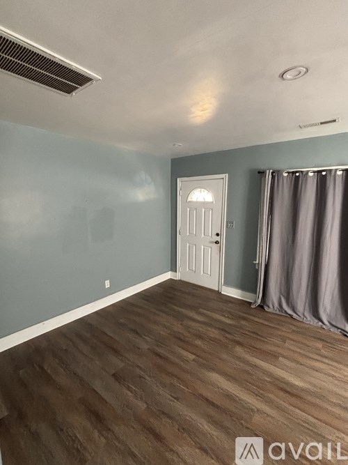 A room with a white door and a grey curtain.